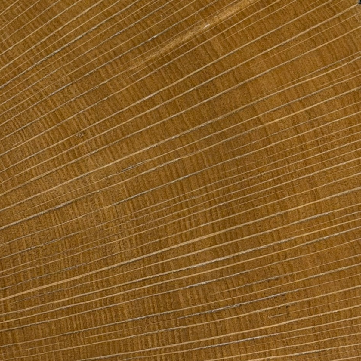 Wafer Coffee Table. A close-up of a warm brown wood grain surface with fine linear texture and subtle variation in tone.