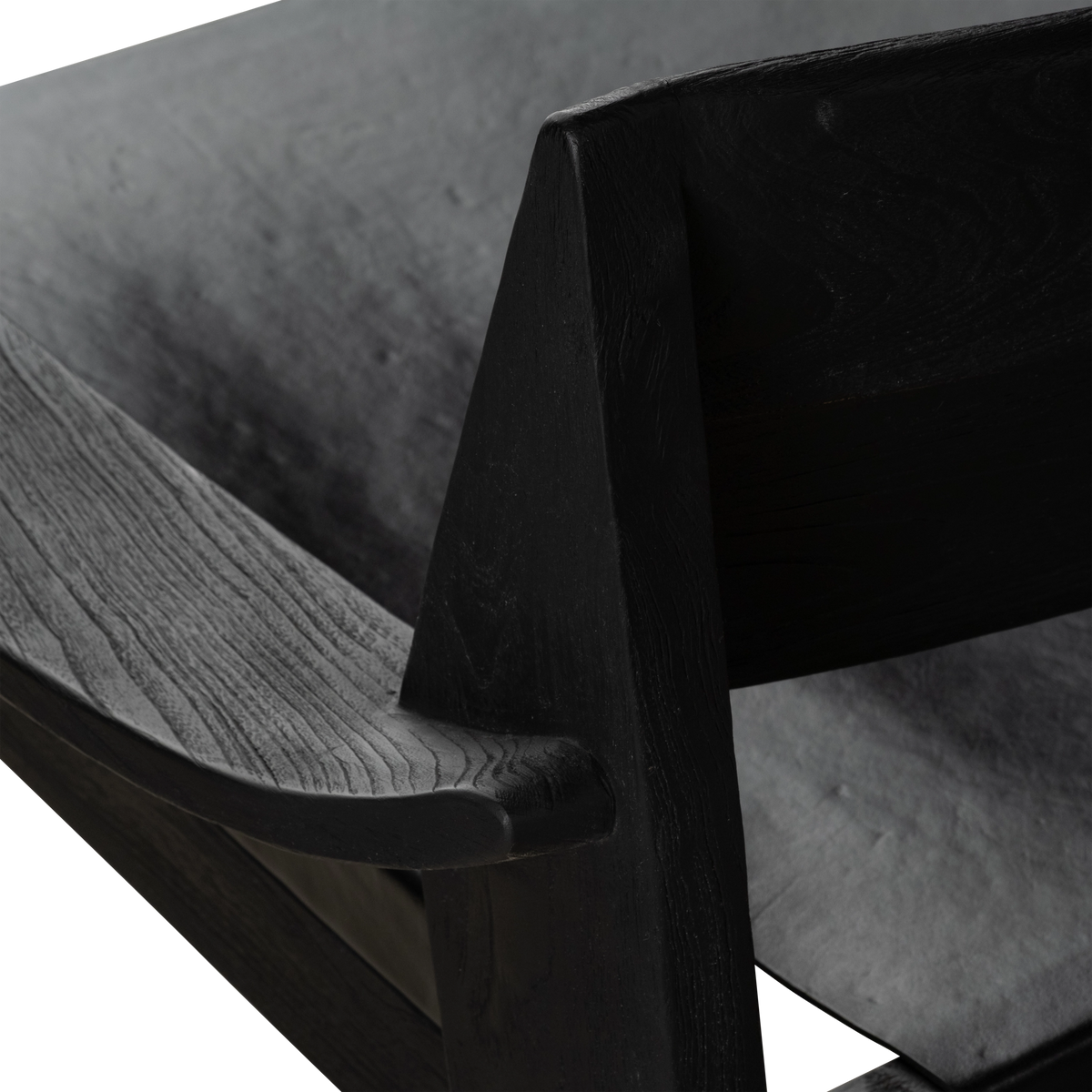 Close-up showing the black teak arm and angled back post of the Leonardo Lounge Chair, with open grain visible against the soft leather seat.