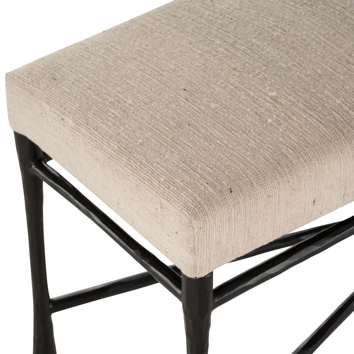 Trevino Bench close-up showing natural textured upholstery over a dark metal frame with tapered legs and cross-bracing.
