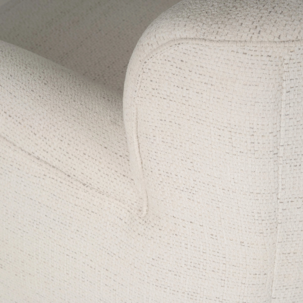 Close-up showing the rounded arm meeting the back panel on the Rowe Swivel Chair in Natural woven fabric, with a stitched seam and an plush, bolstered arm.