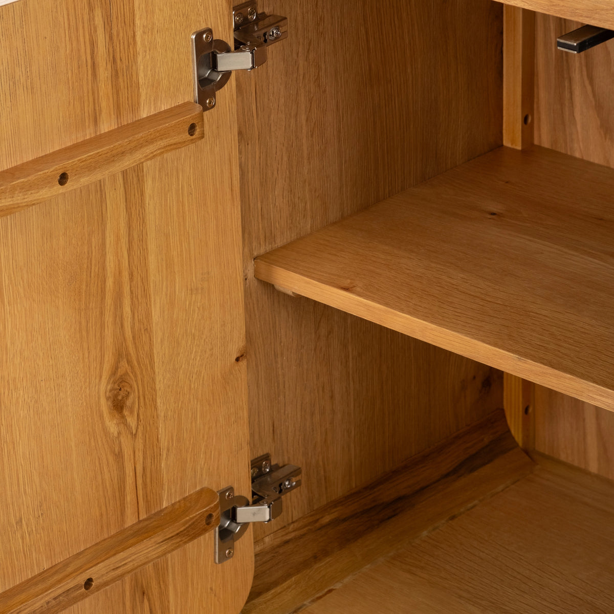 Interior close-up of the Edge Cabinet in honey oak, showing a metal hinge, an interior shelf and the wood battens on the back of the door.