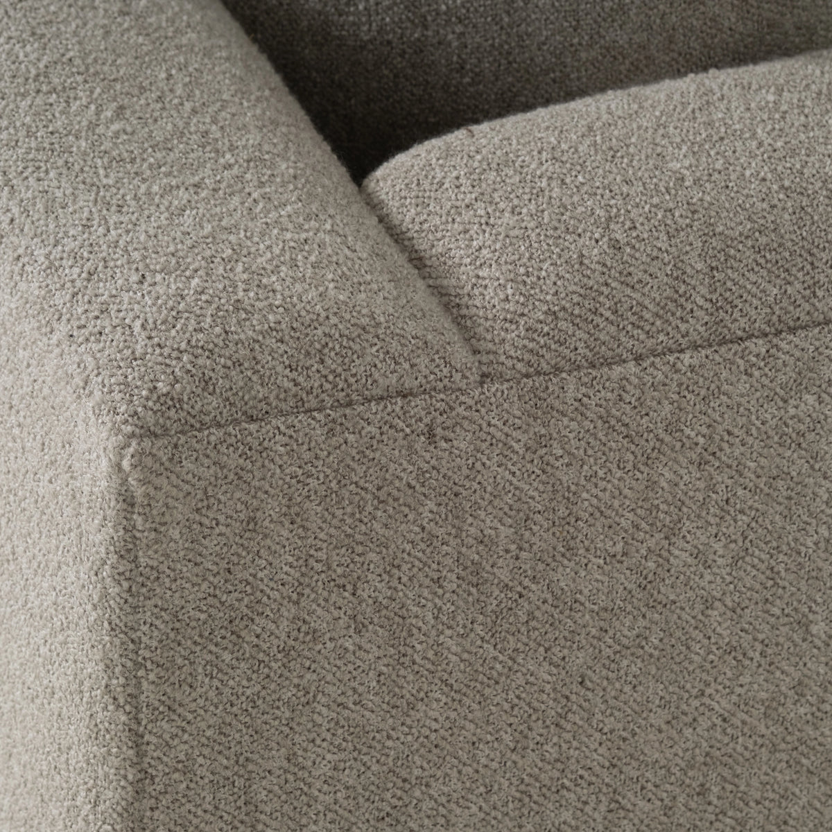 Close-up showing the arm, seat, and back of the Ease Sofa in Pebble textured fabric, with a nubby bouclé-like weave and a stitched seam at the corner.