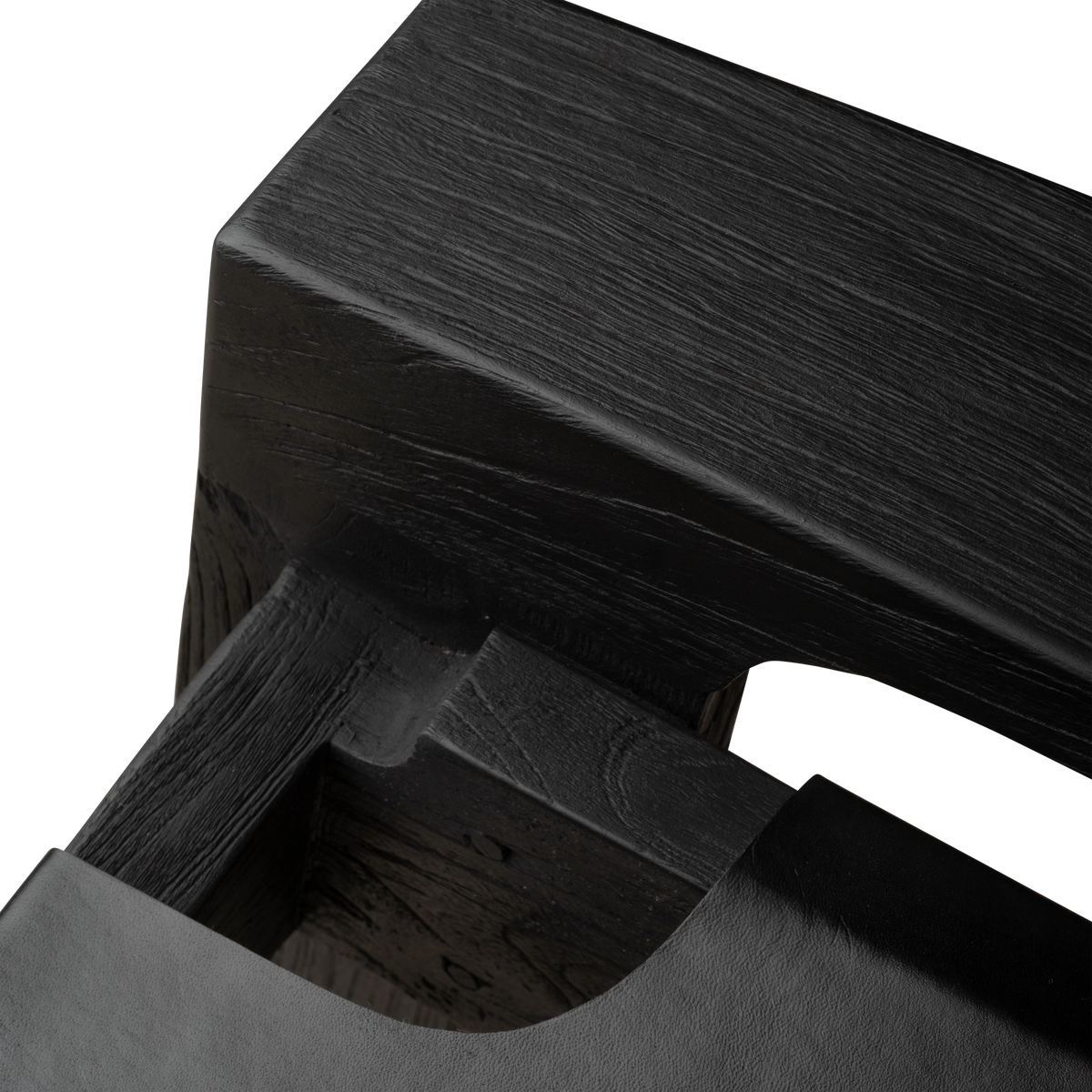 Close-up of the Leonardo Lounge Chair’s black teak frame and seat joinery, showing the carved wood notch, textured grain, and the leather edge wrapping in.