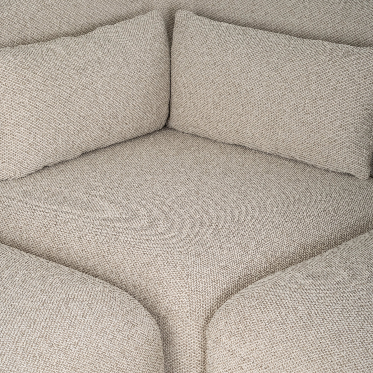 Duncan Modular Sectional corner seat in Oatmeal woven fabric, with two lumbar pillows meeting at the corner and softly rounded arms on either side.