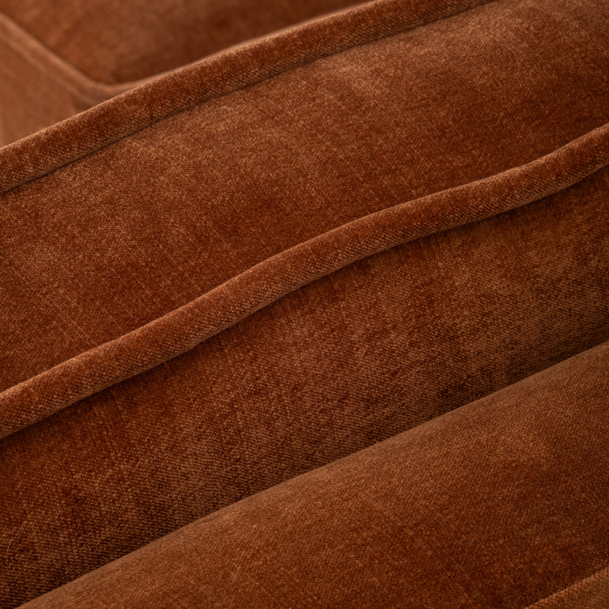 Close-up showing the Loom Modular Armless Chair in rust chenille, with the double piped seam running along the cushion edge and the soft folds of the fabric.